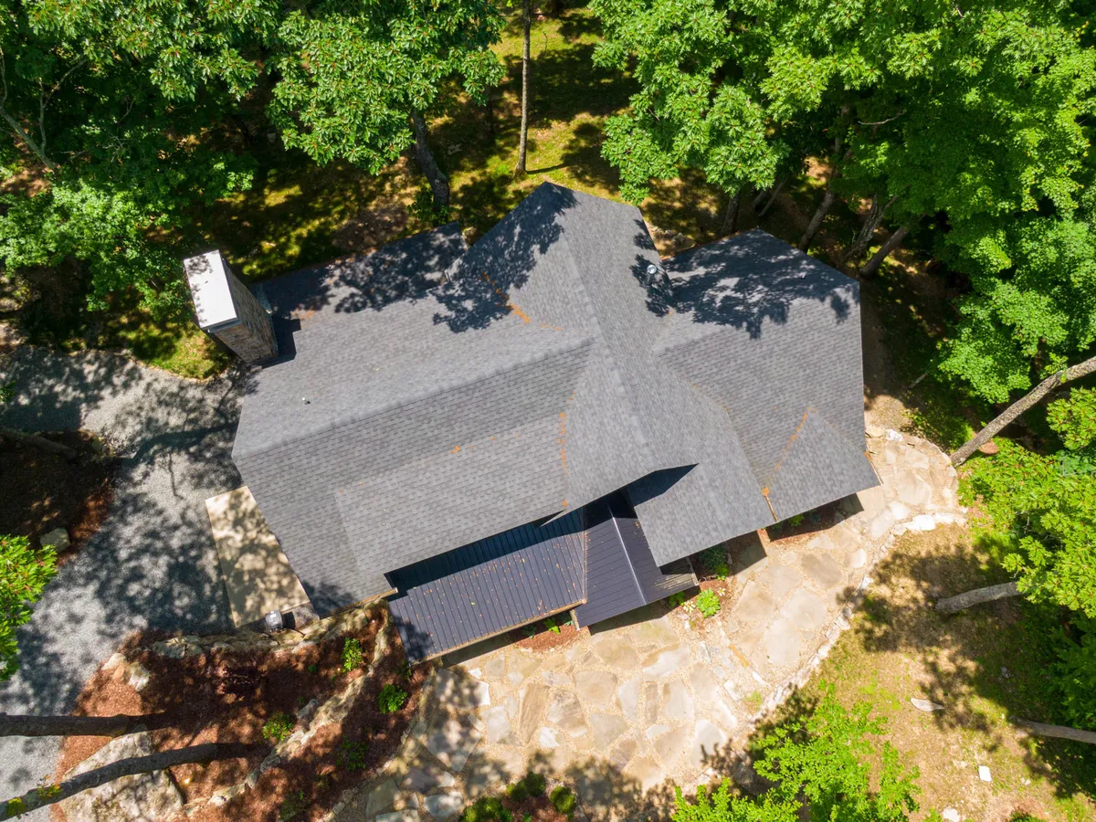 A tranquil exterior view of the home set amid lush trees, with a stone pathway inviting exploration. The surrounding woods and open space highlight opportunities for nature walks and outdoor fun.