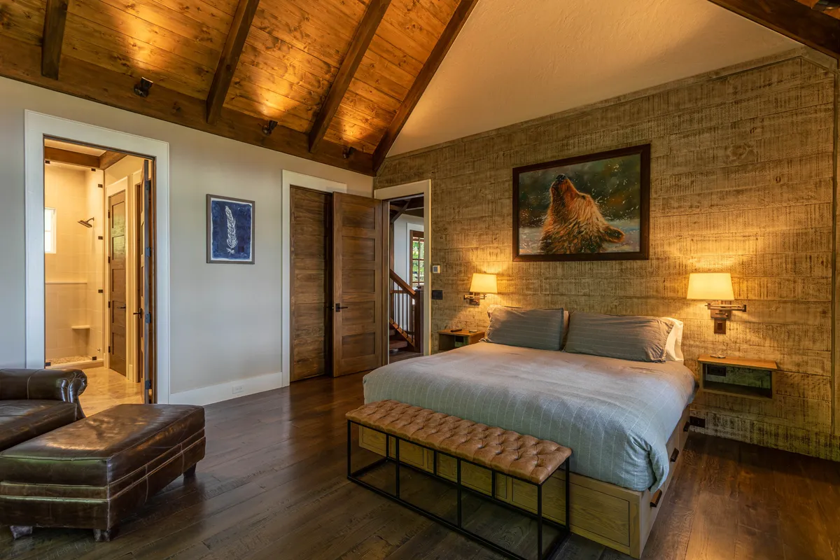 A tranquil bedroom featuring a comfortable bed with soft bedding, stylish artwork on the wall, matching nightstands, and warm lighting fixtures. Natural light streams in through the windows, creating an inviting and restful atmosphere.