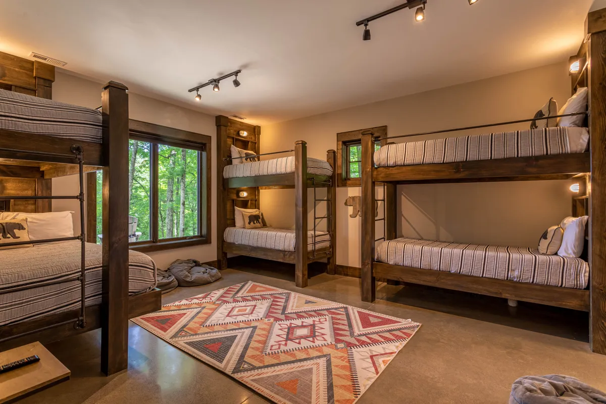 A playful, kid-friendly interior with bunk beds, a cozy area rug, and a window offering views of the outdoors. The space is designed for fun and creativity, perfect for sleepovers, games, and late-night storytelling sessions.